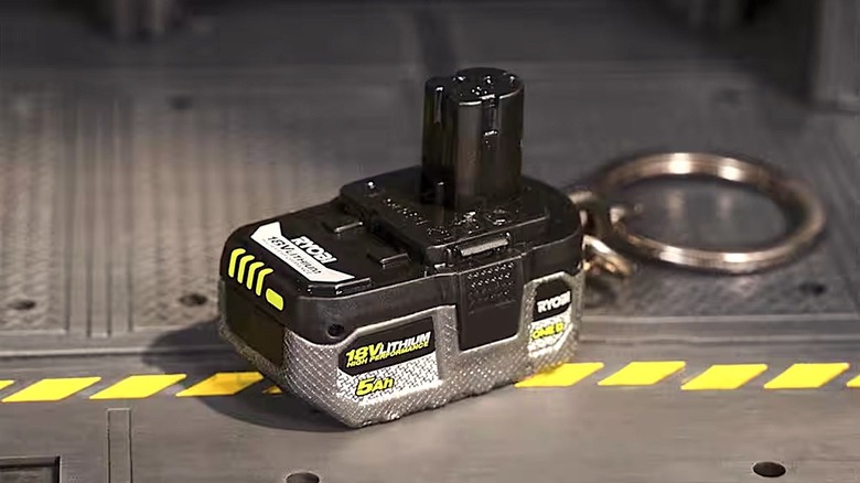 A miniature Ryobi 18V Battery keychain on metal platform