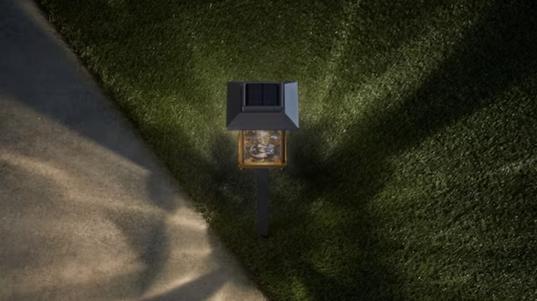 A single Hampton Bay Parkwood Bronze solar light illuminates sidewalk and Astroturf