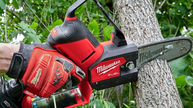 Person cutting tree with Milwaukee M12 Fuel 6-inch Brushless Pruning Hatchet Mini Chainsaw