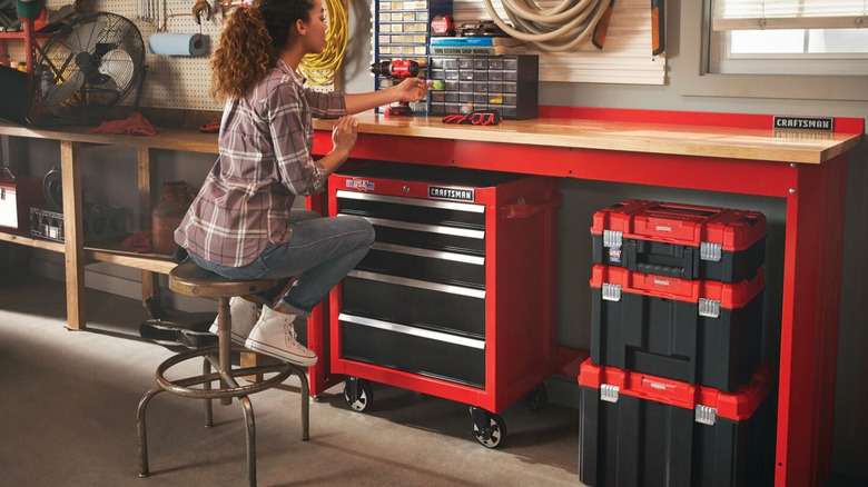 A person in a workshop surrounded by Craftsman toolboxes and tool cabinets.