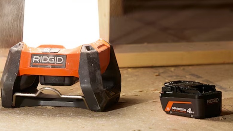 Ridgid 18V Cordless 360° Area Light on the ground next to a 4.0 Ah battery