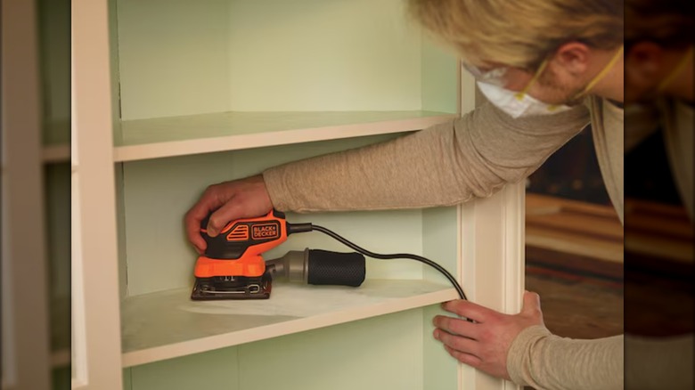 using Black+Decker sheet sander on a bookcase