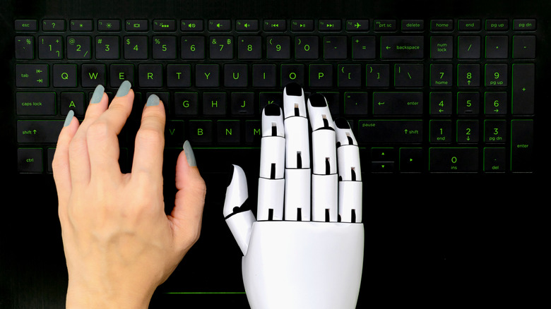 robot and human hands on keyboard