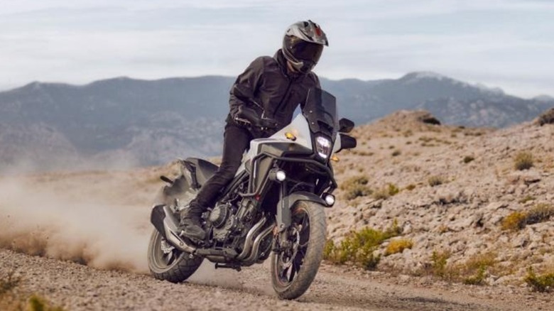 A Honda NX500 rider blasting down a dusty backroad.