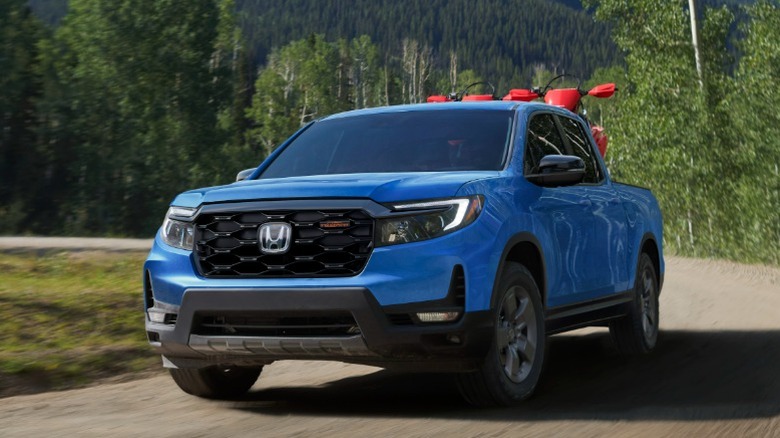 Blue Honda Ridgeline driving down a forested dirt road