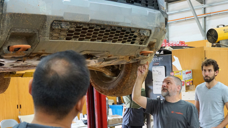 Honda senior engineer Pete Langseth points to 2026 Honda Passport tow hook on a lift