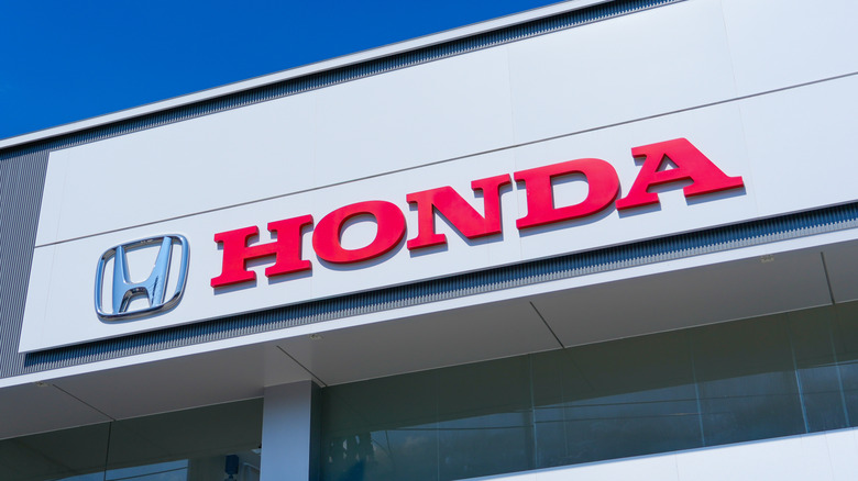 The current Honda Logo in silver and the words "Honda" in red on the side of a building