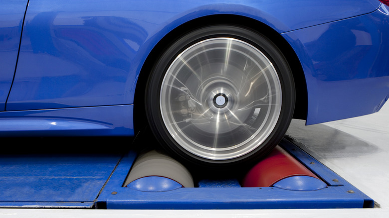A blue car sits on a chassis dynamometer