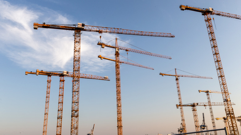 Several stationary boom cranes at construction site