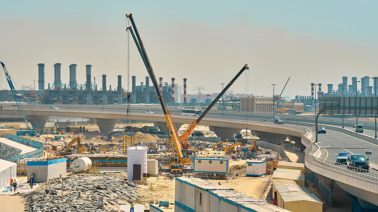 Telescopic cranes working on construction site near freeway