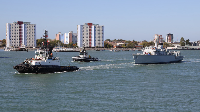 Tugs tow the ex-Royal Navy mine countermeasures vessel ATHERSTONE towards the harbour mouth