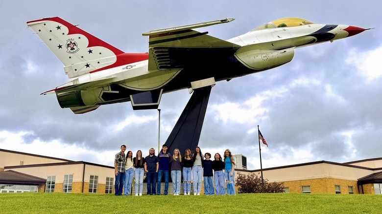 Group of students standing below the F-16 Thunderbirds fighter mounted on a pedestal In Union High Schooll