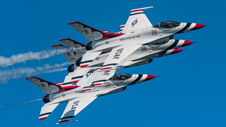 Four Thunderbirds F-16 fighters flying in close formation in a cloudless sky