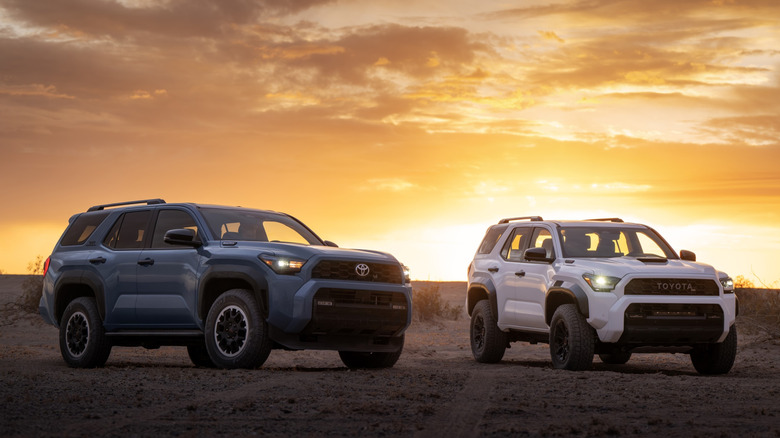 Front view of blue and white Toyota 4Runners parked in desert at sunset.