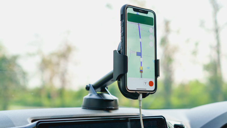 A phone mounted on a car's dashboard showing GPS directions.