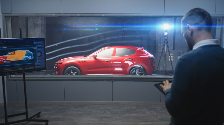 Engineer works on car undergoing wind tunnel testing