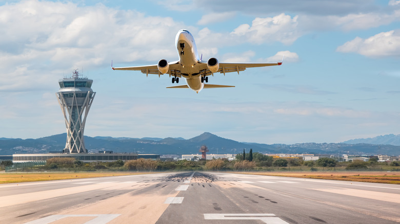 White Passenger plane fly up over take-off runway from airport - El Prat-Barcelona airport.