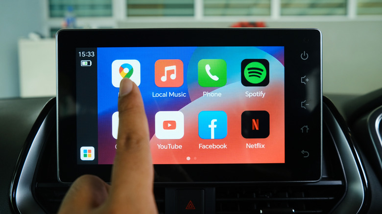 Close-up of a finger selecting the Google Maps icon on an Android Auto interface