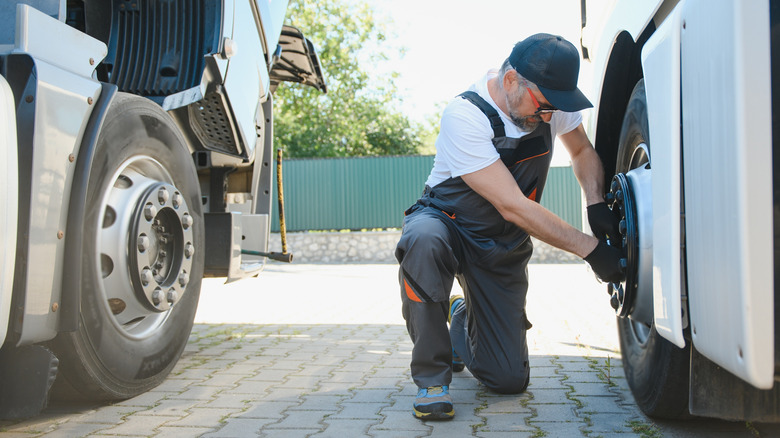 A man removing nuts from semi-truck rim.