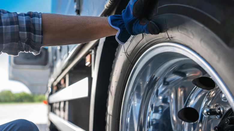 A man checking the newly installed tire of a semi-truck.