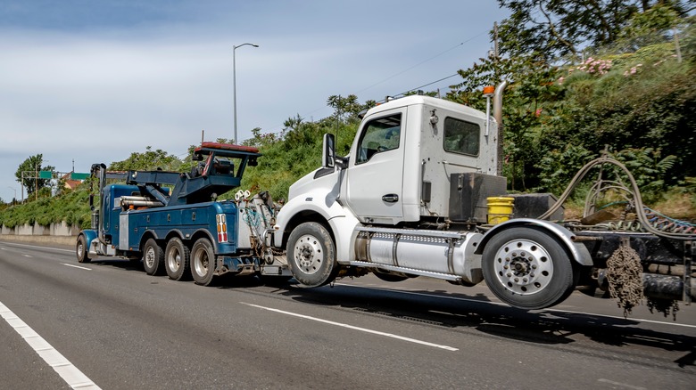 A blue tow truck towing a white semi