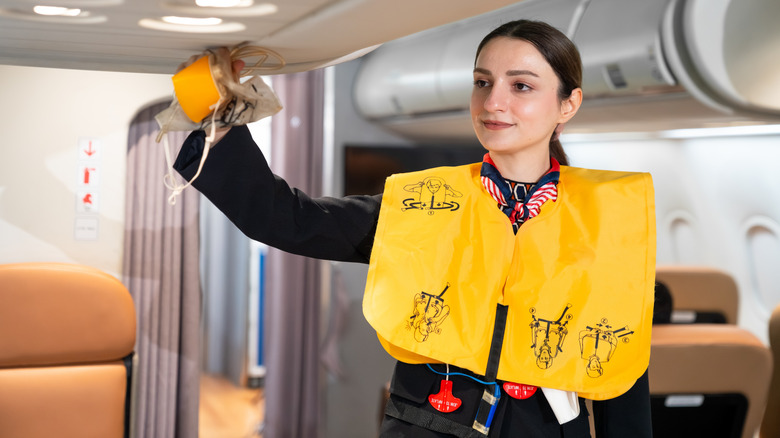 An air hostess demonstrates safety procedures on a commercial jet.