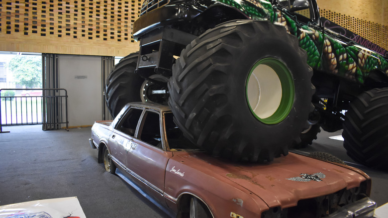 Monster truck front wheels parked over old car