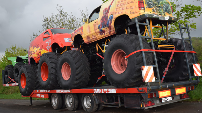 Two monster trucks loaded on a flatbed truck
