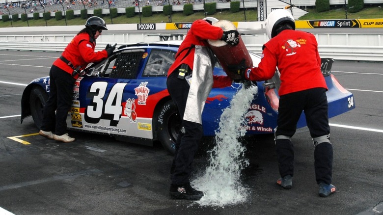 a pit crew spilling fuel while refueling a NASCAR cup car