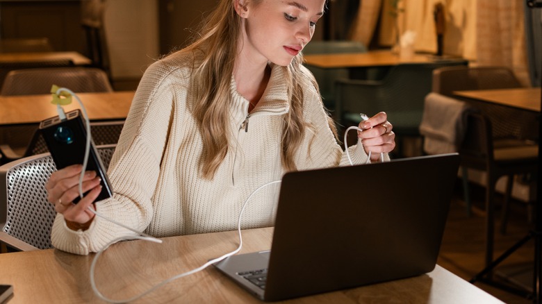Woman holding power bank connected to laptop