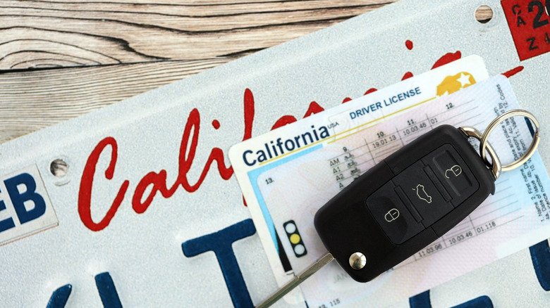 Close up view of car keys on top of California driver license and license plate.
