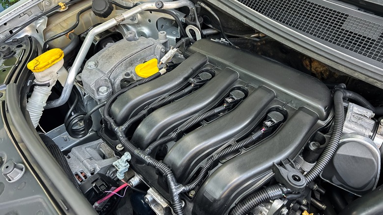 A close-up shot of a high-performance car engine, featuring a sleek black intake manifold,