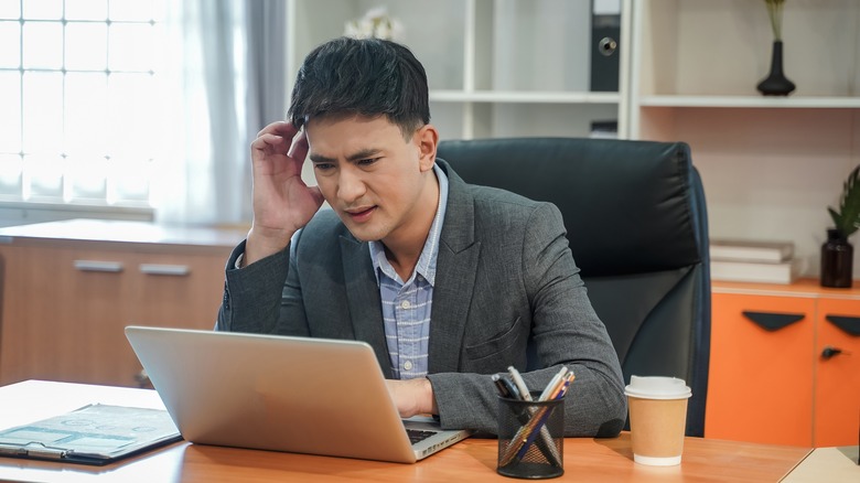 A man checking his laptop looking panicked