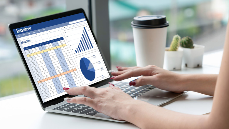 Woman working on spreadsheets on a laptop with coffee