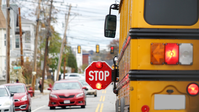 A rear view of a school bus with its red lights and stop sign activated