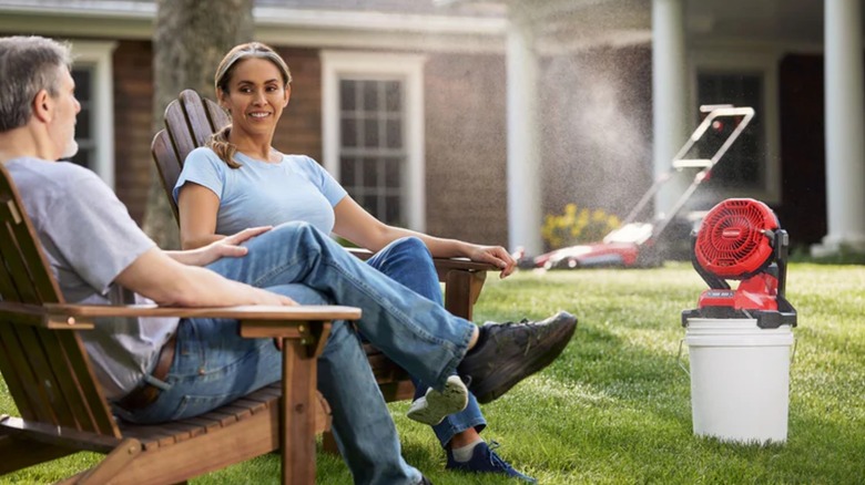 man and woman sitting in front of misting fan