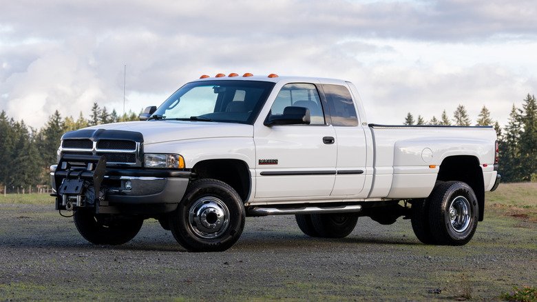 A white Dodge Ram 3500 HD with dually rear wheels, front 3/4 view, white exterior, extended cab
