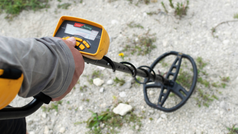 metal detector in hand while working in a field