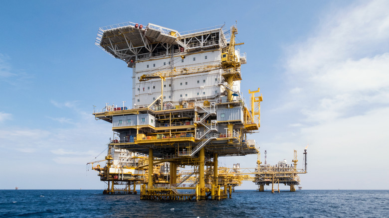 A low angle shot of 3 off-shore oil rigs in the ocean.