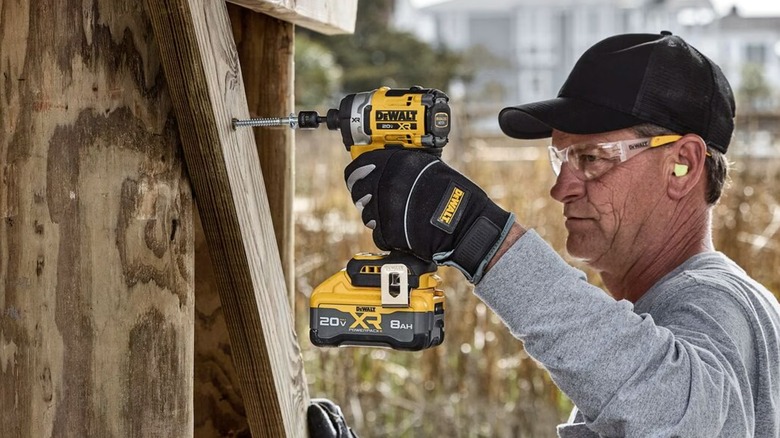 A person using a DeWalt impact driver on wood.