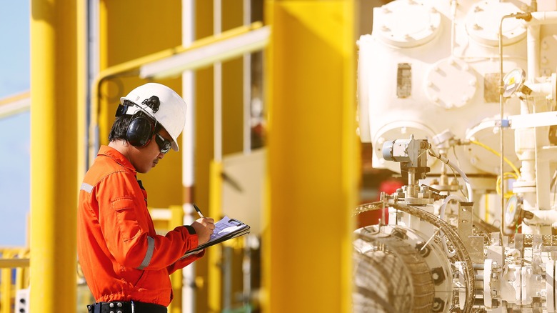 An operator recording operation of oil and gas process at an oil rig.
