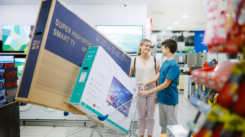 woman and young boy with two TVs in their shopping cart