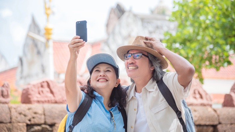 A man and a woman smiling and taking a selfie while on vacation