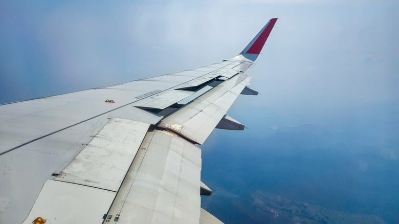 View from the airplane cabin window during descent with spoilers extended during approach