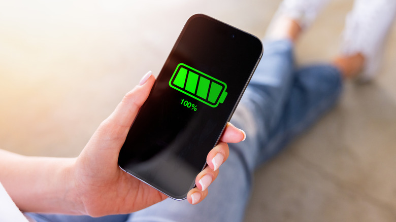 A woman holding mobile phone with full battery icon.
