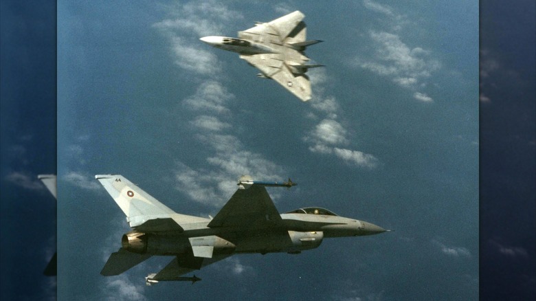An F-16 Fighting Falcon and an F-14 Tomcat engaged in a mock dogfight