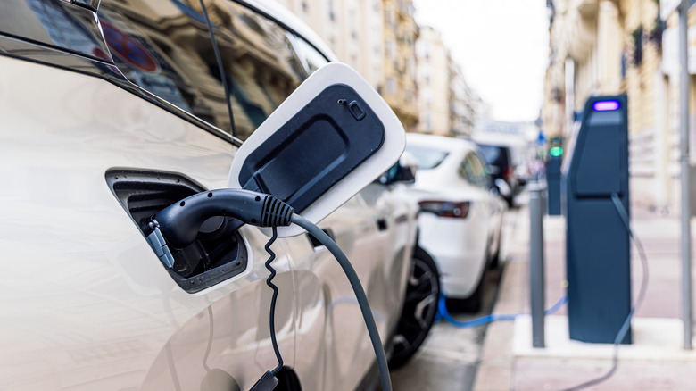 Side shot of a PHEV car using a charging station in the city.