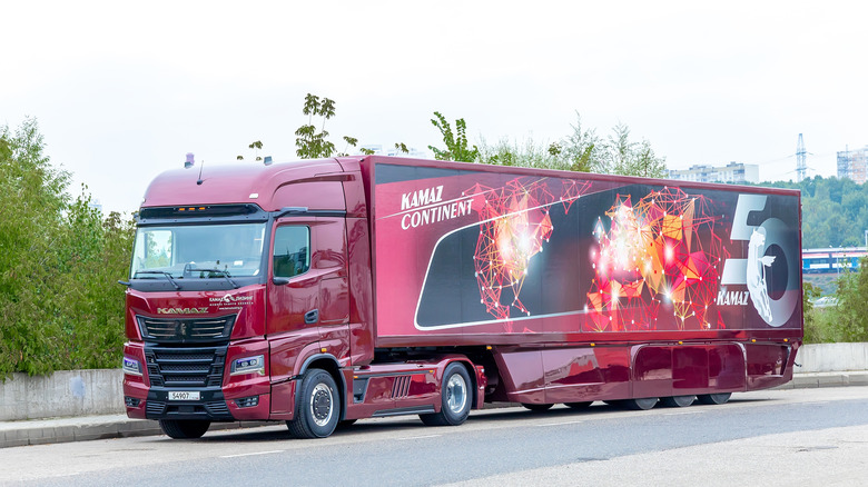 Red hybrid semi-truck driving down road
