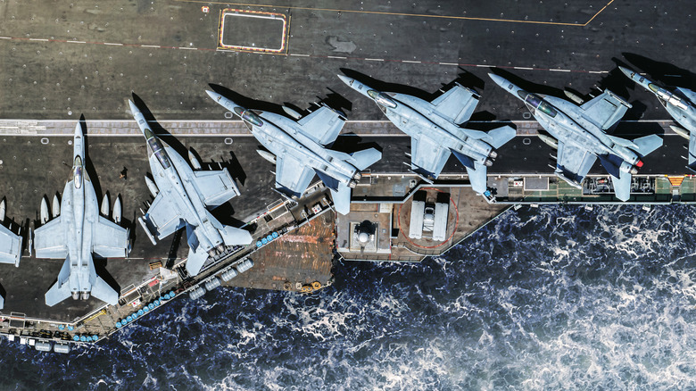 F/A-18E Super Hornet is parked on an American military aircraft carrier at sea.