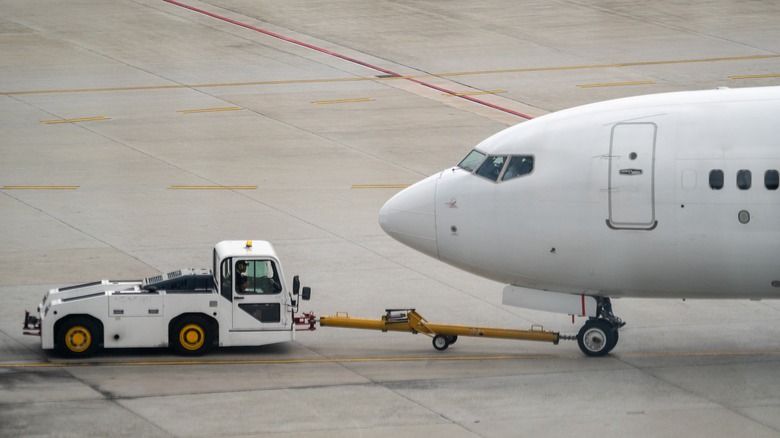Pushback tug approaches plane on tarmac.